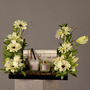 A tray with a box containing a diffuser and a candle, decorated with various types of white flowers