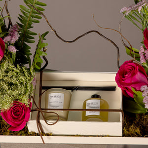 A tray with a box containing a diffuser and a candle, decorated with various types of pink flowers