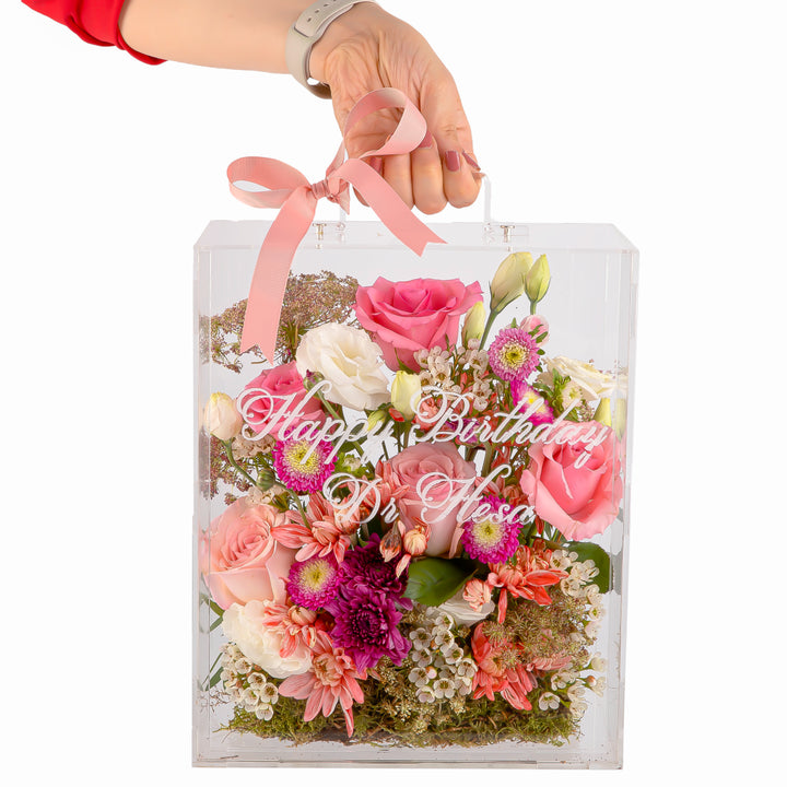 An Acrylic box filled with different types of flowers with customized name