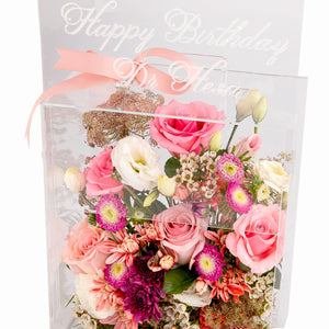 An Acrylic box filled with different types of flowers with customized name