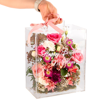 An Acrylic box filled with different types of flowers with customized name