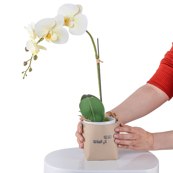 White orchid flower in a beige leather vase decorated with customized name 