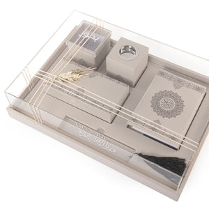 A beige set contains Quraan, incense burner, box, bakhor box, and bookmark in an acrylic box