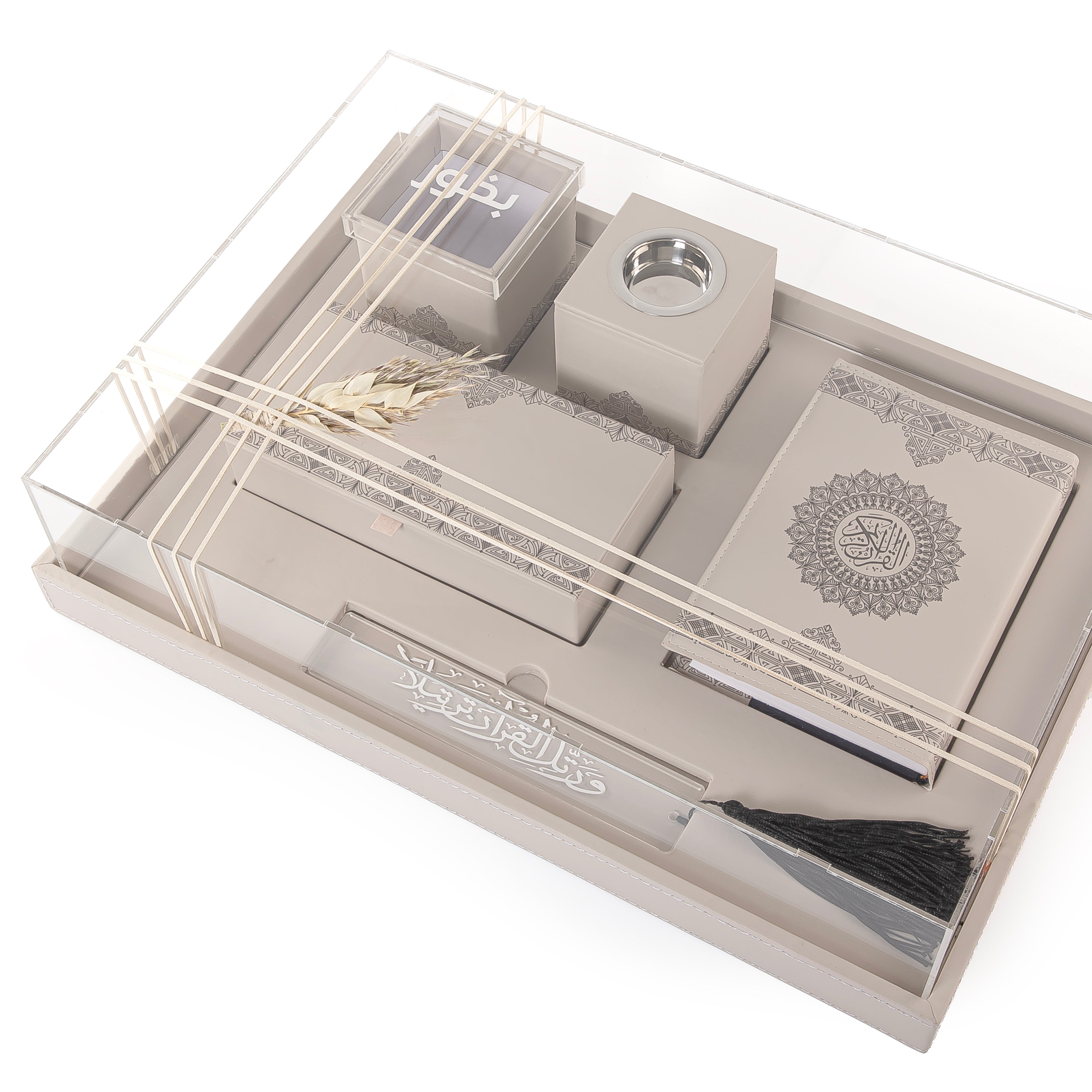A beige set contains Quraan, incense burner, box, bakhor box, and bookmark in an acrylic box