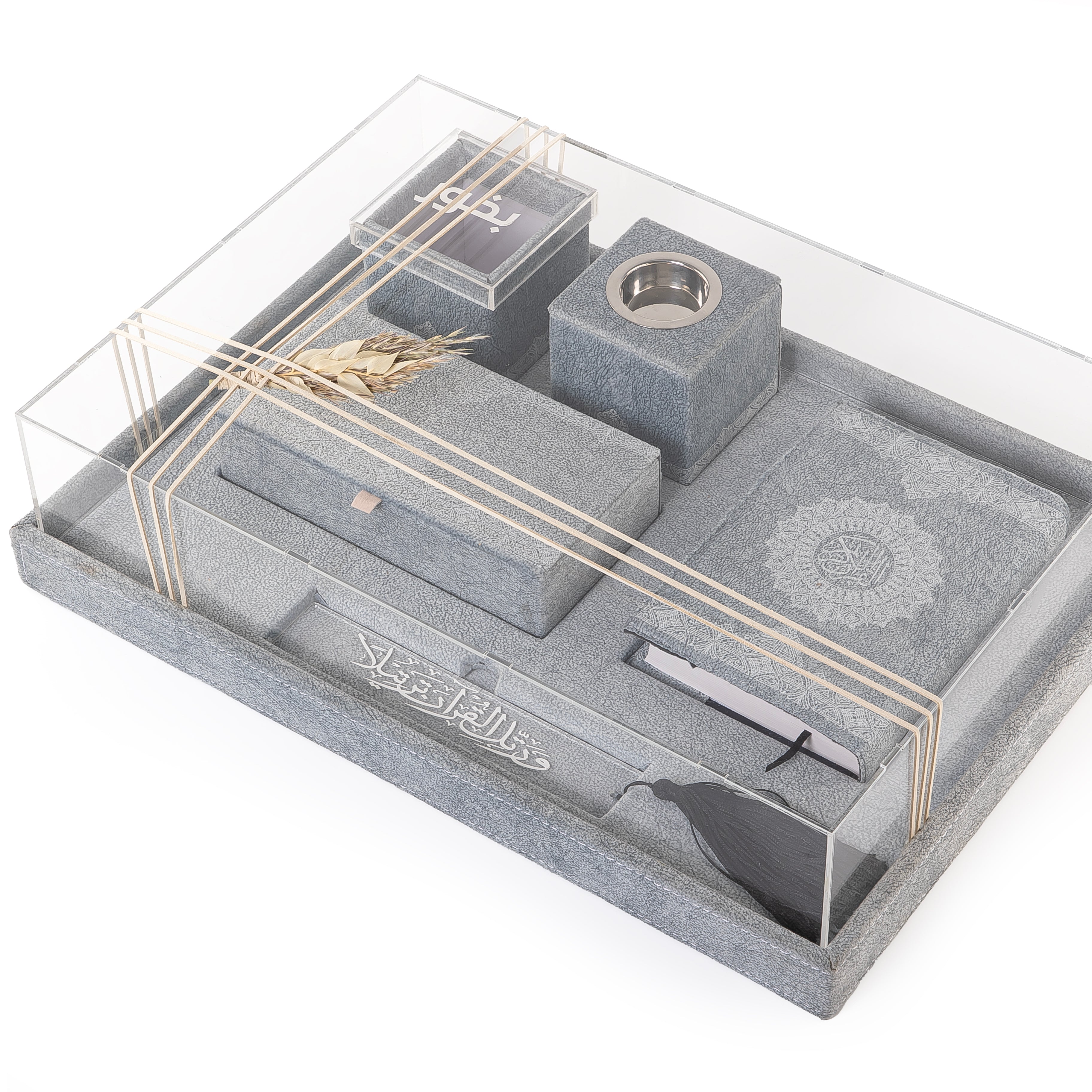 A grey set contains Quraan, incense burner, box, bakhor box, and bookmark in an acrylic box