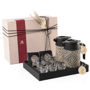 A black tray holding two thermoses with fabric covers, six coffee glasses, six tea glasses, six coasters, three labels "Tea, Karak, Coffee" with a gift box