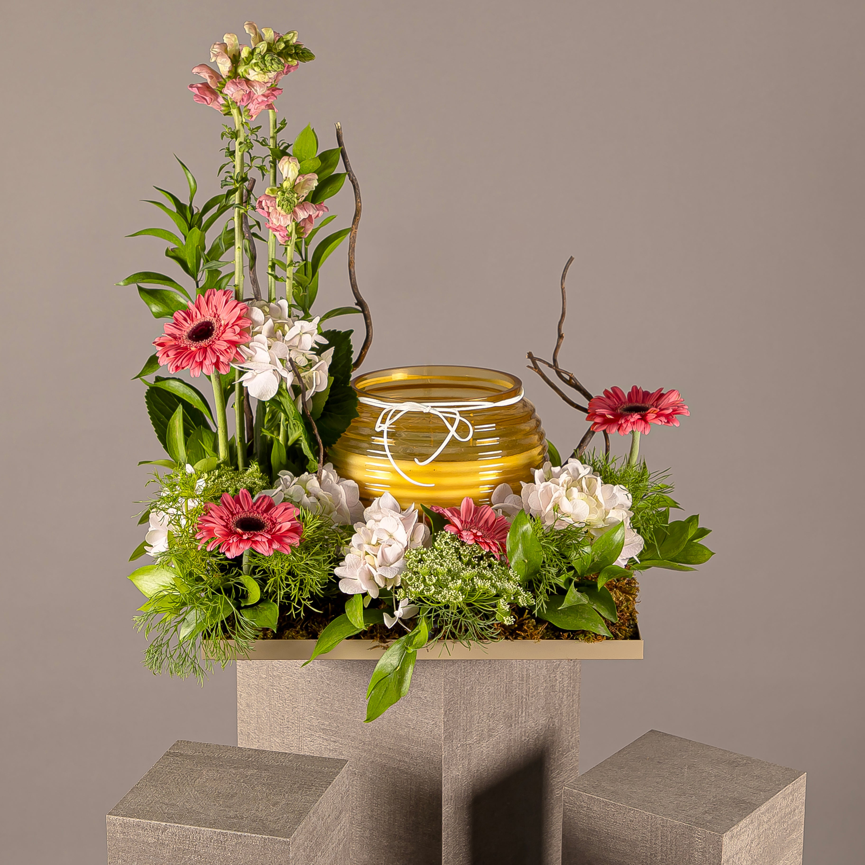 A flower tray with yellow glass candle