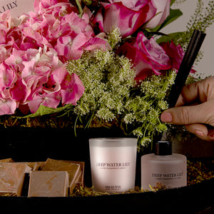 A chocolate tray with a box containing a diffuser and candle, decorated with various types of pink flowers