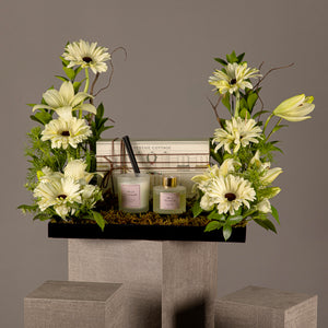 A tray with a box containing a diffuser and a candle, decorated with various types of white flowers