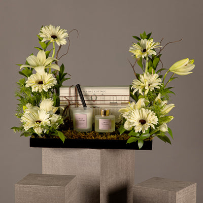 A tray with a box containing a diffuser and a candle, decorated with various types of white flowers