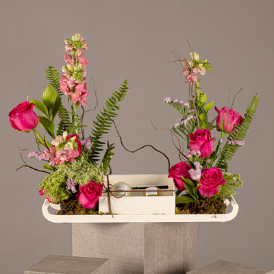 A tray with a box containing a diffuser and a candle, decorated with various types of pink flowers