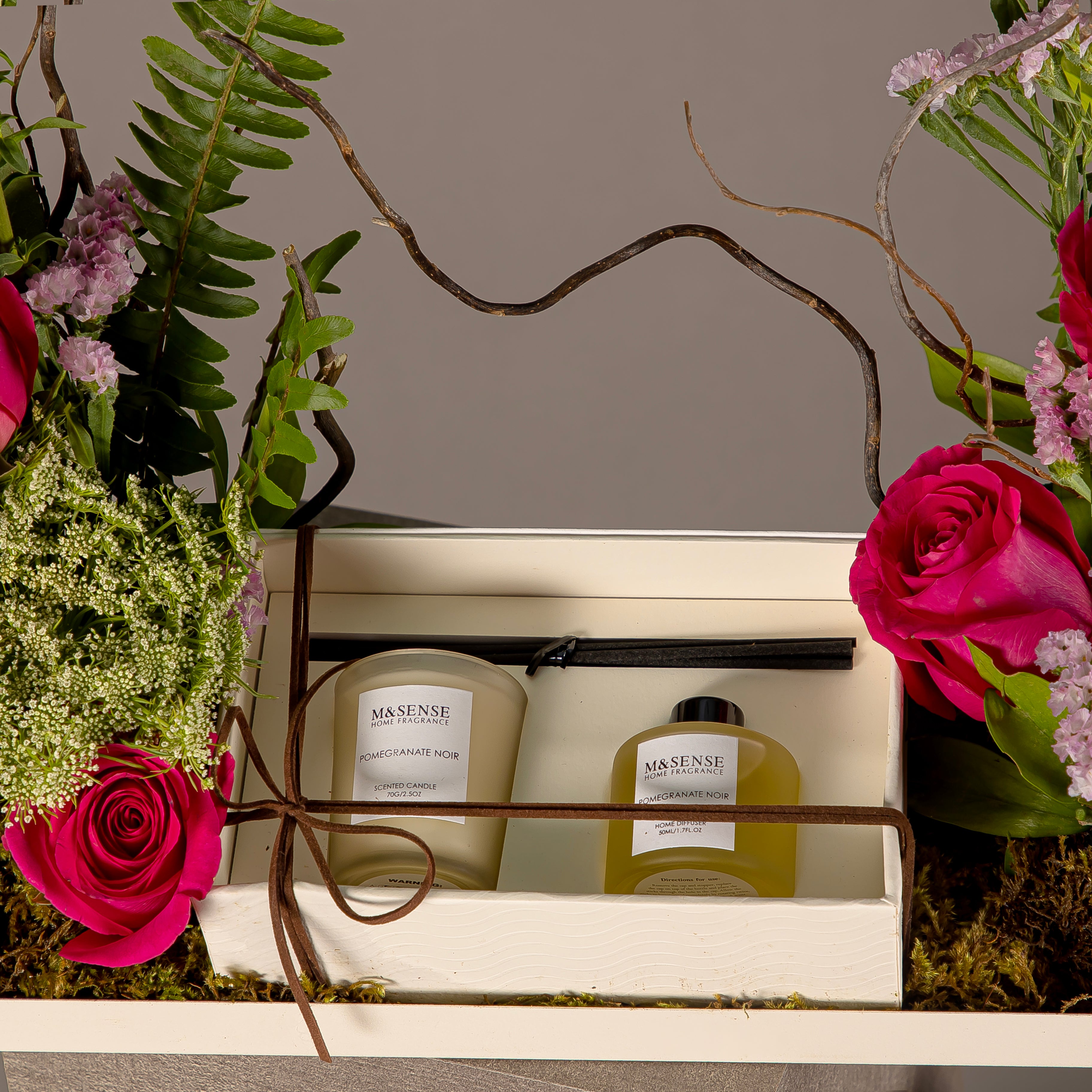 A tray with a box containing a diffuser and a candle, decorated with various types of pink flowers