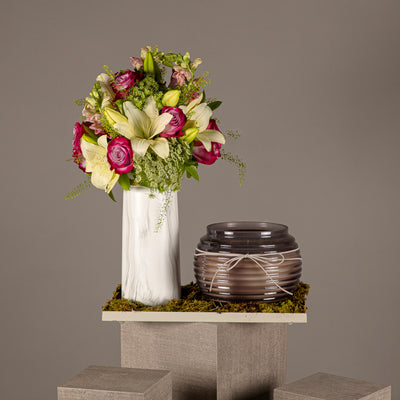 A tray with a flower vase of white lilies and pink roses, and a black glass candle