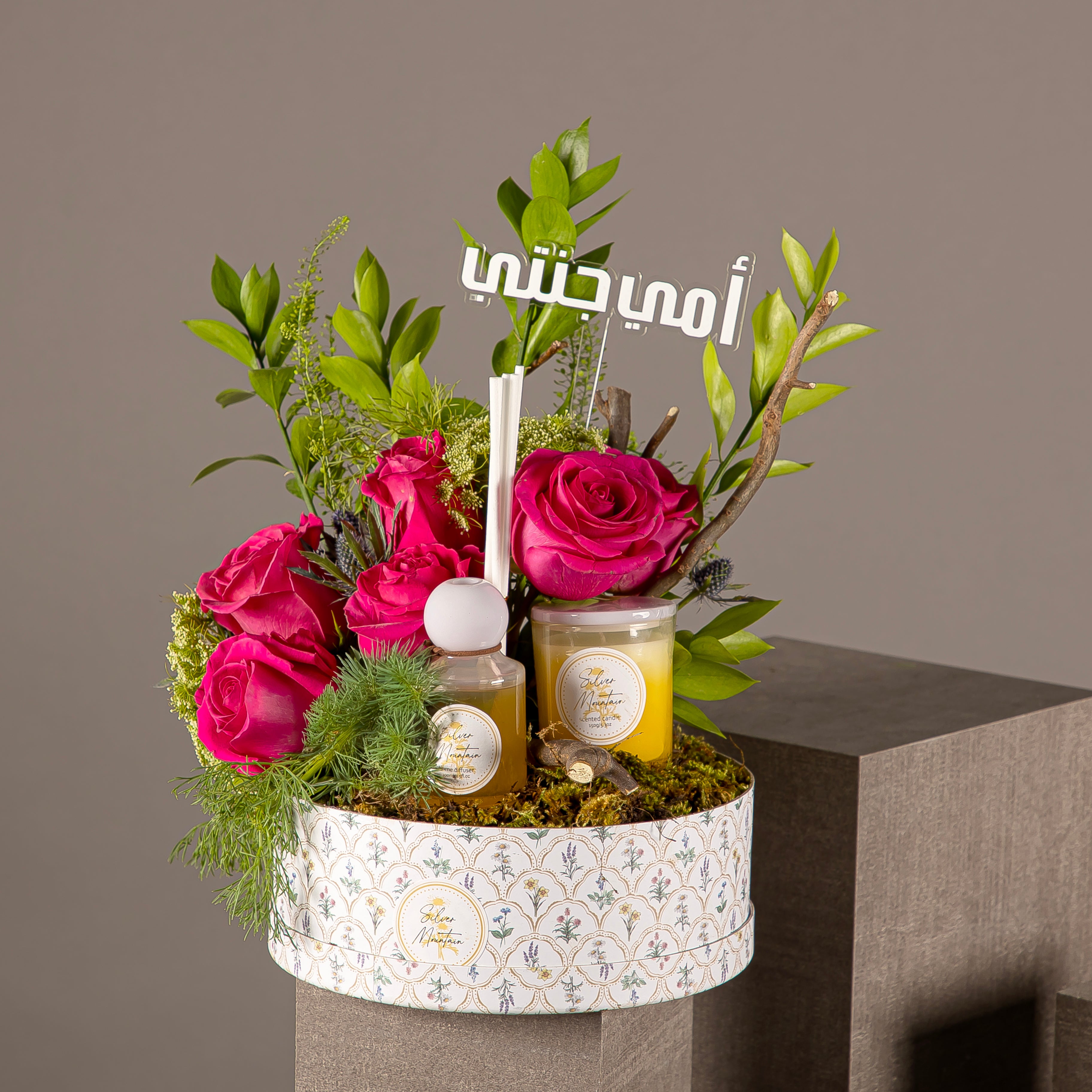 pink roses in a circular box with diffuser and candle
