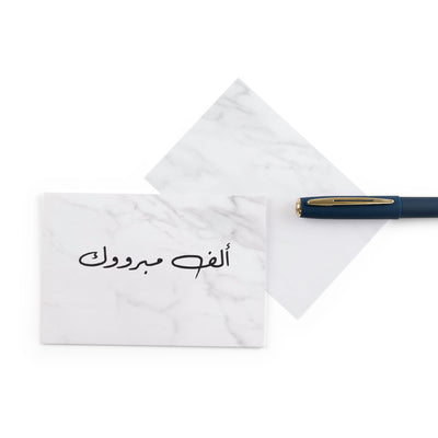 white marble greeting card with the words 'ألف مبروك' written on it