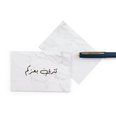 white marble new baby girl greeting card with the words 'تتربى بعزكم' written on it